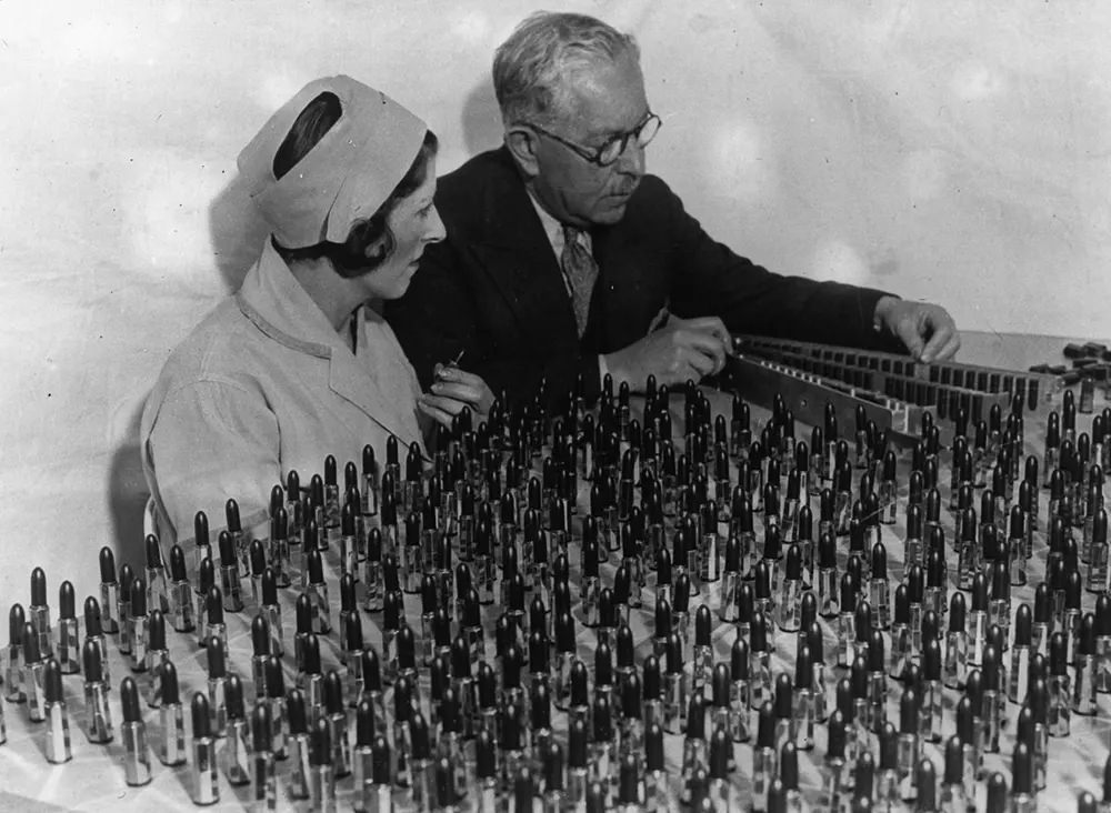 Factor and Ray Judd look over an array of lipstick shades. 1932.