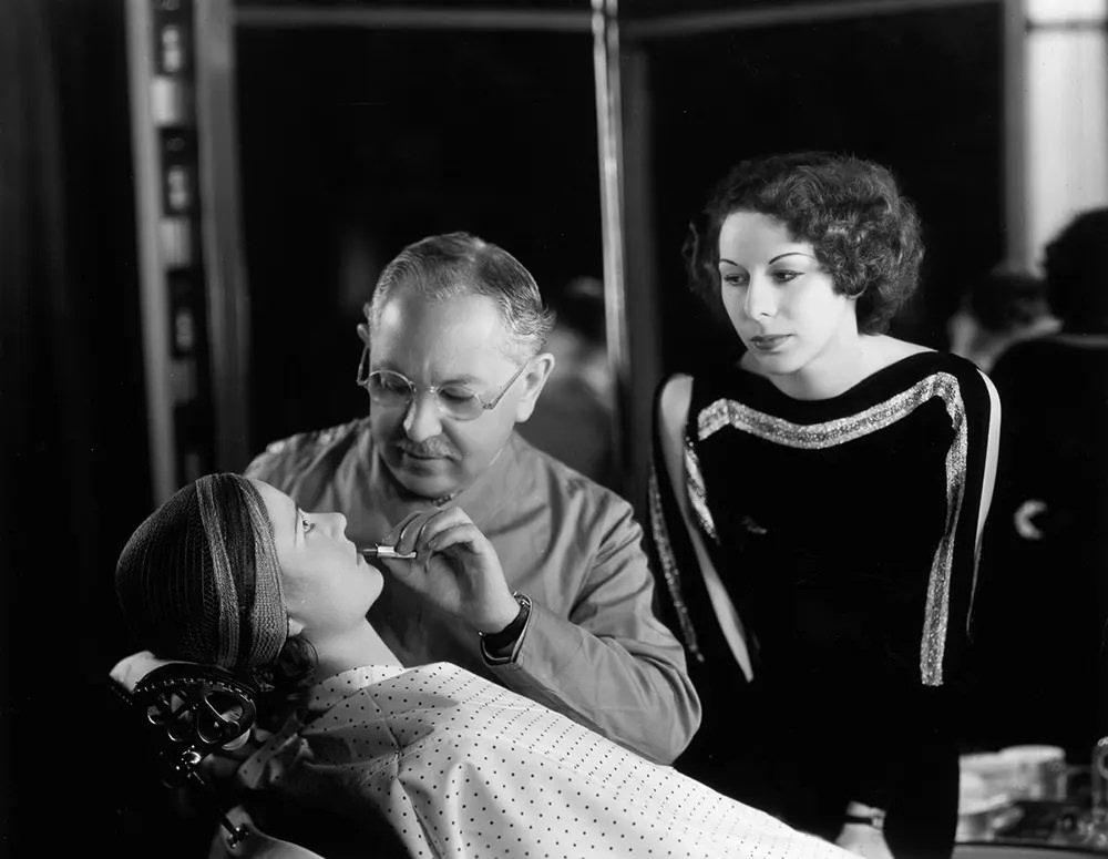 Factor demonstrates a technique for applying lipstick. 1930.