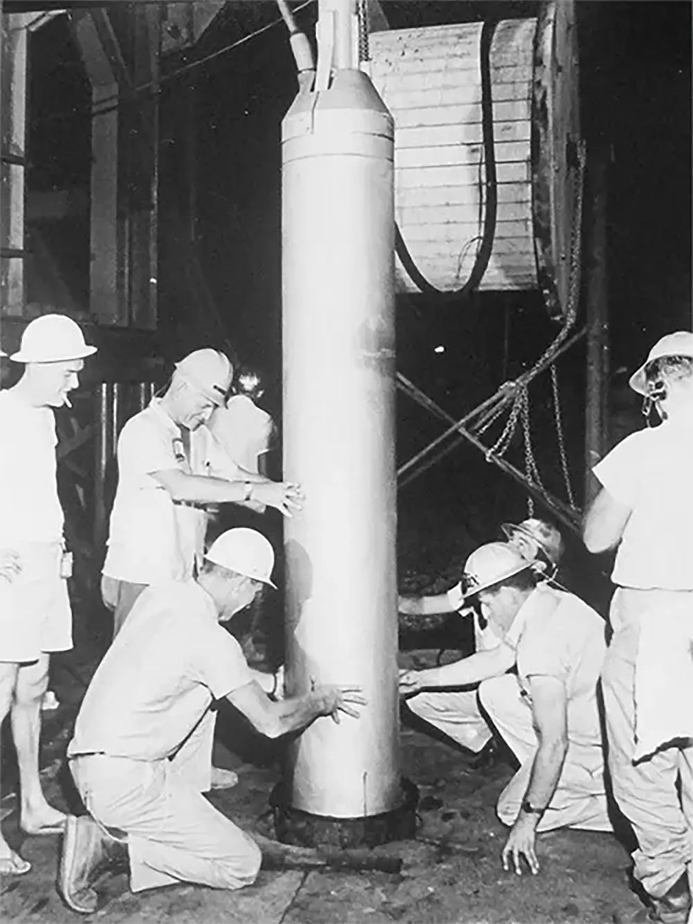 Workers lower the 5.3-kiloton bomb used in the Salmon test into the ground.