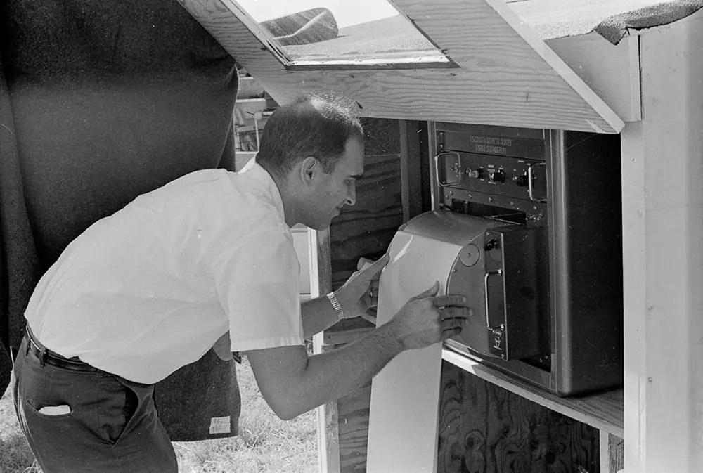 A scientist checks a seismograph at an observation point.