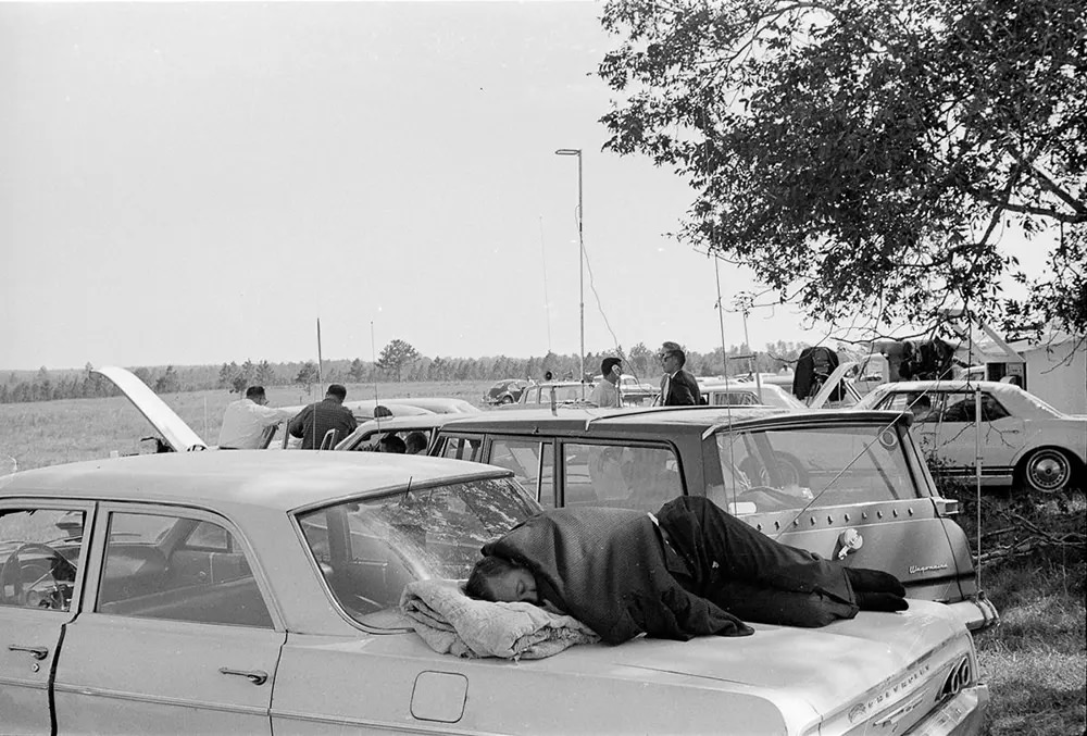 A reporter naps on his car at the media observation point during a postponement.