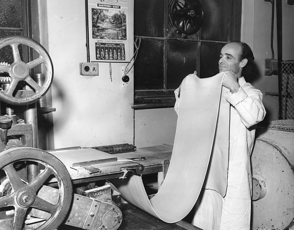 Mr Martinez feeds a length of pasta into a macaroni-making machine at Messrs L Ugo Ltd, London.