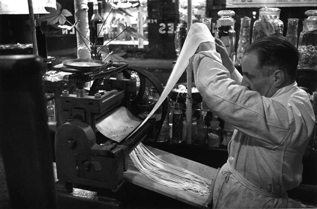 Lengths of pasta are cut into strips by machine in Recchioni's restaurant 'King Bomba' in London's Soho, 1939