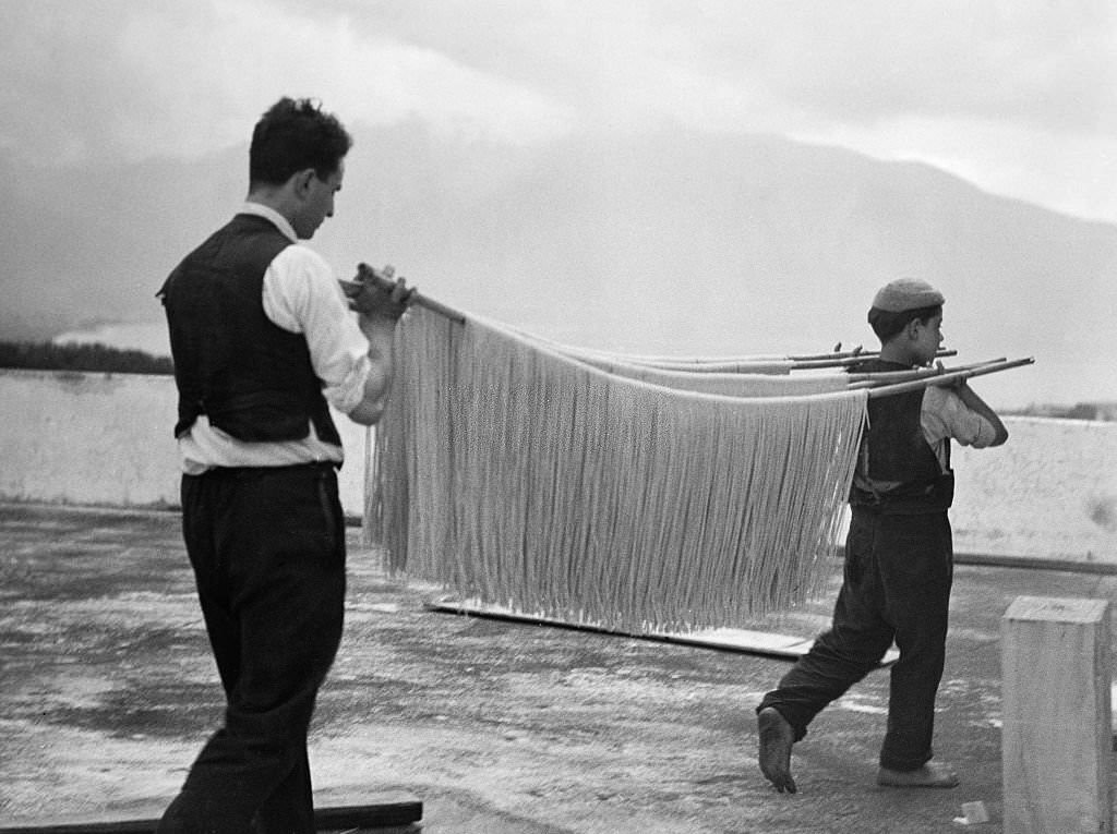Spaghetti production Carrying spaghetti on a bamboo stick to dry them, 1932