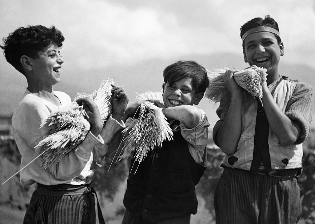 Three Neapolitan boys carrying a bundle of spaghetti, 1932