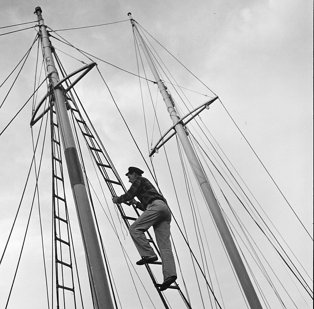 A man climbs up the mast of a sailboat, Provincetown, Massachusetts, 1948.