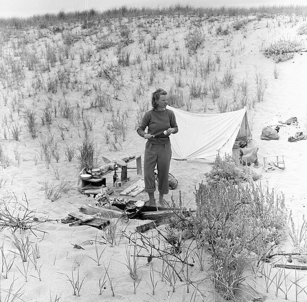 View of a young woman who has set up camp in the sand dunes of the beach, Provincetown, Massachusetts, 1948.