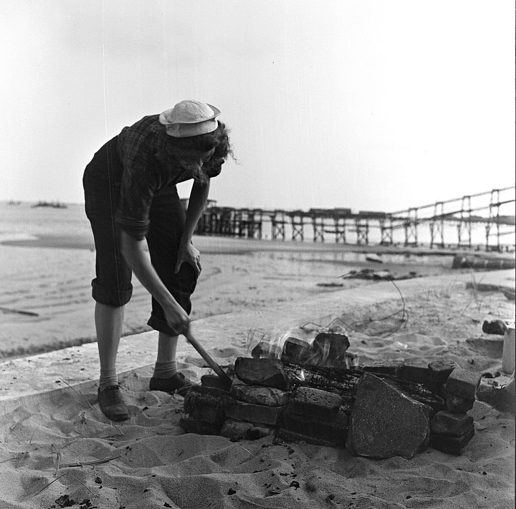 A woman tends the fire for a beachside cookout, Provincetown, Massachusetts, 1948.
