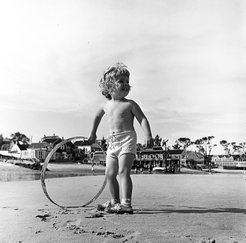 A young child plays with a hoop on the beach, Provincetown, Massachusetts, 1948.