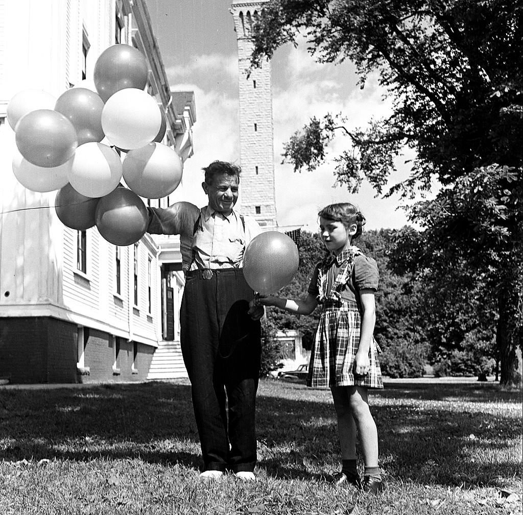 A young girl picks a balloon from a bunch sold by a balloon seller, Provincetown, Massachusetts, 1948.
