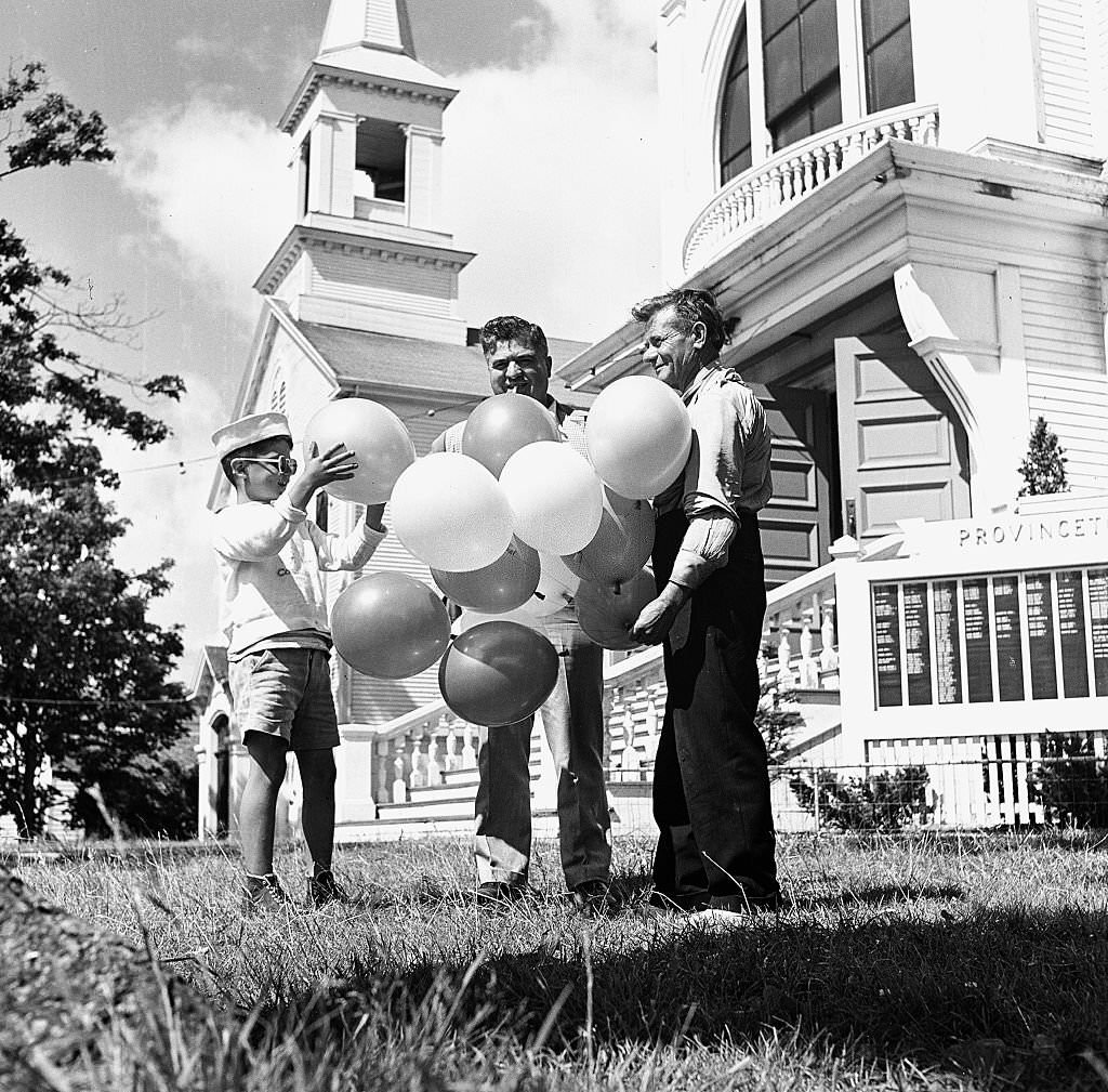 A young boy picks a balloon from a bunch sold by a balloon seller, Provincetown, Massachusetts, 1948.