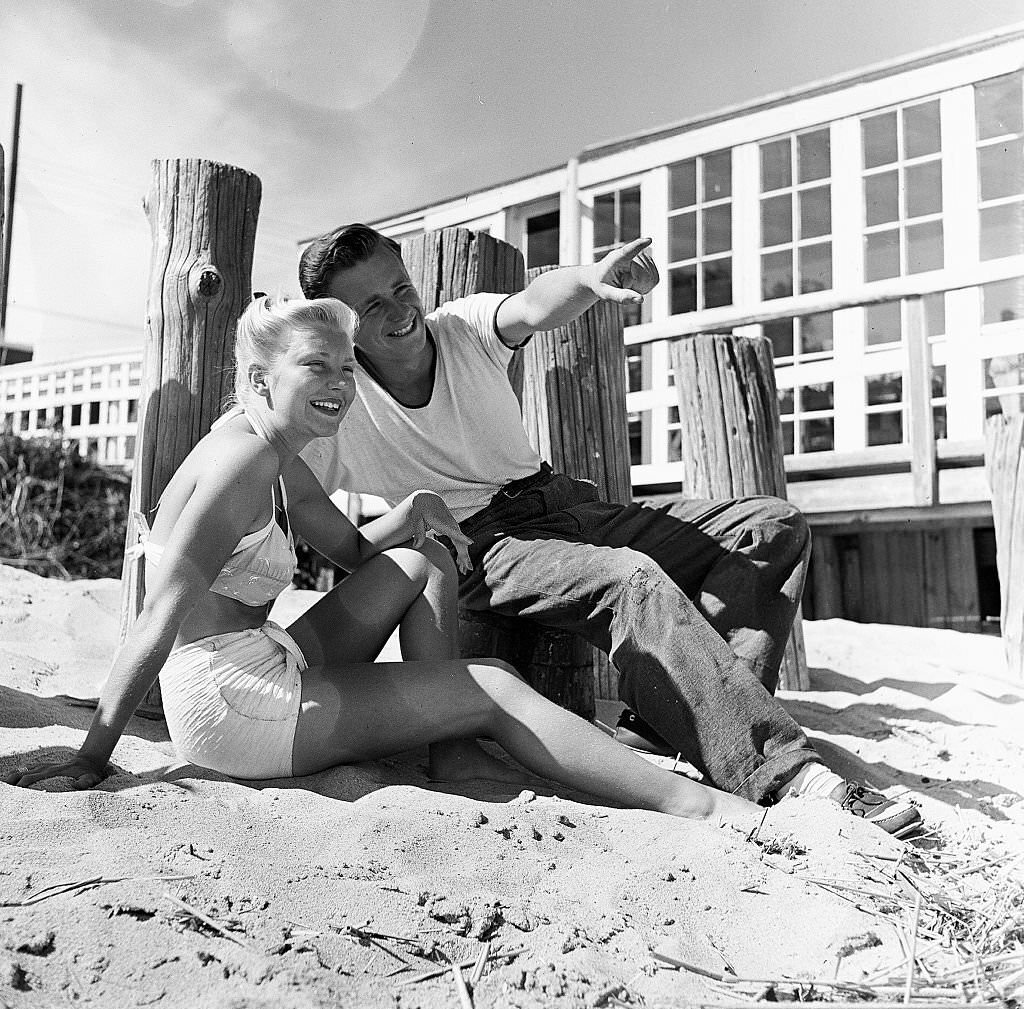 A man points out something in the distance to a woman as they sit on the beach on Cape Cod, Provincetown, Massachussetts, 1947.