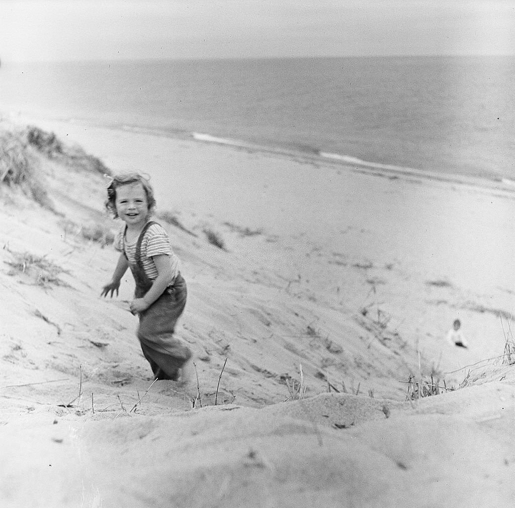 A small girl smiles while walking on the beach on Cape Cod, Provincetown, Massachussetts, 1947.