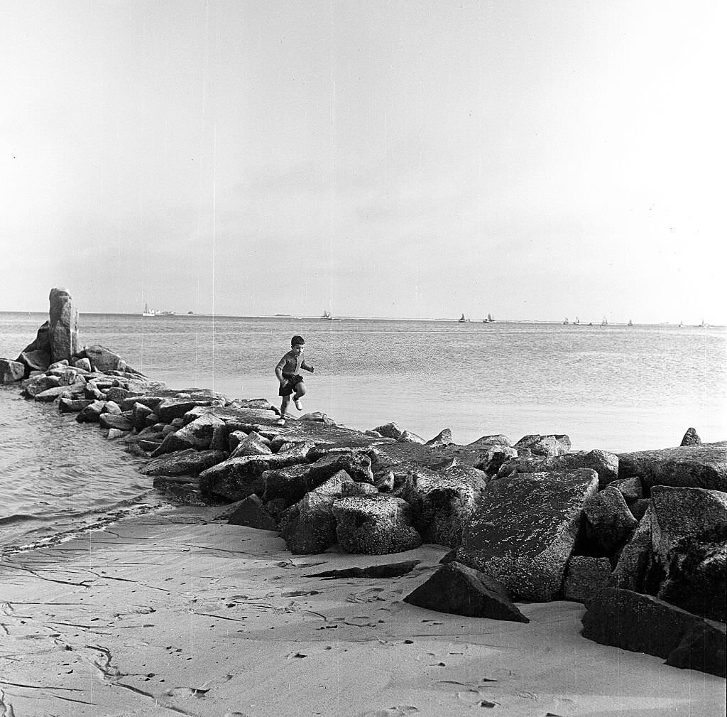 A young boy runs on a rocky breakwater on the beach, Provincetown, Massachusetts, 1948.