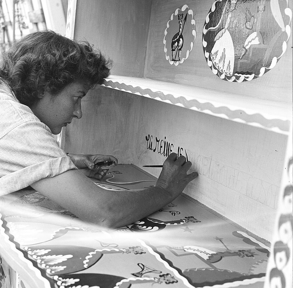 An employee hand paints text onto a cabinet, at an antique shop, Provincetown, Massachusetts, 1948.