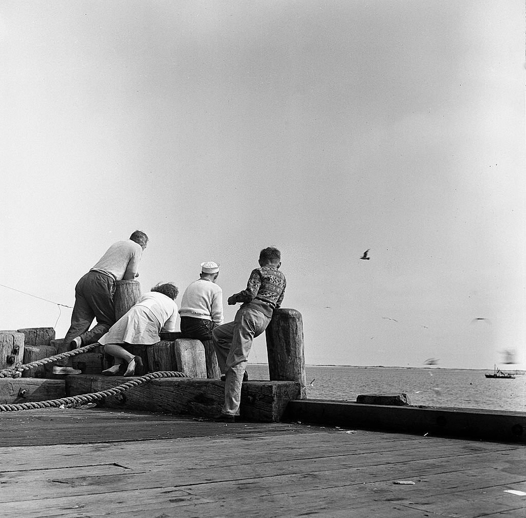 A man and a woman, with two boys, look out onto the ocean from a pier on Cape Cod, Provincetown, Massachussetts, 1947.