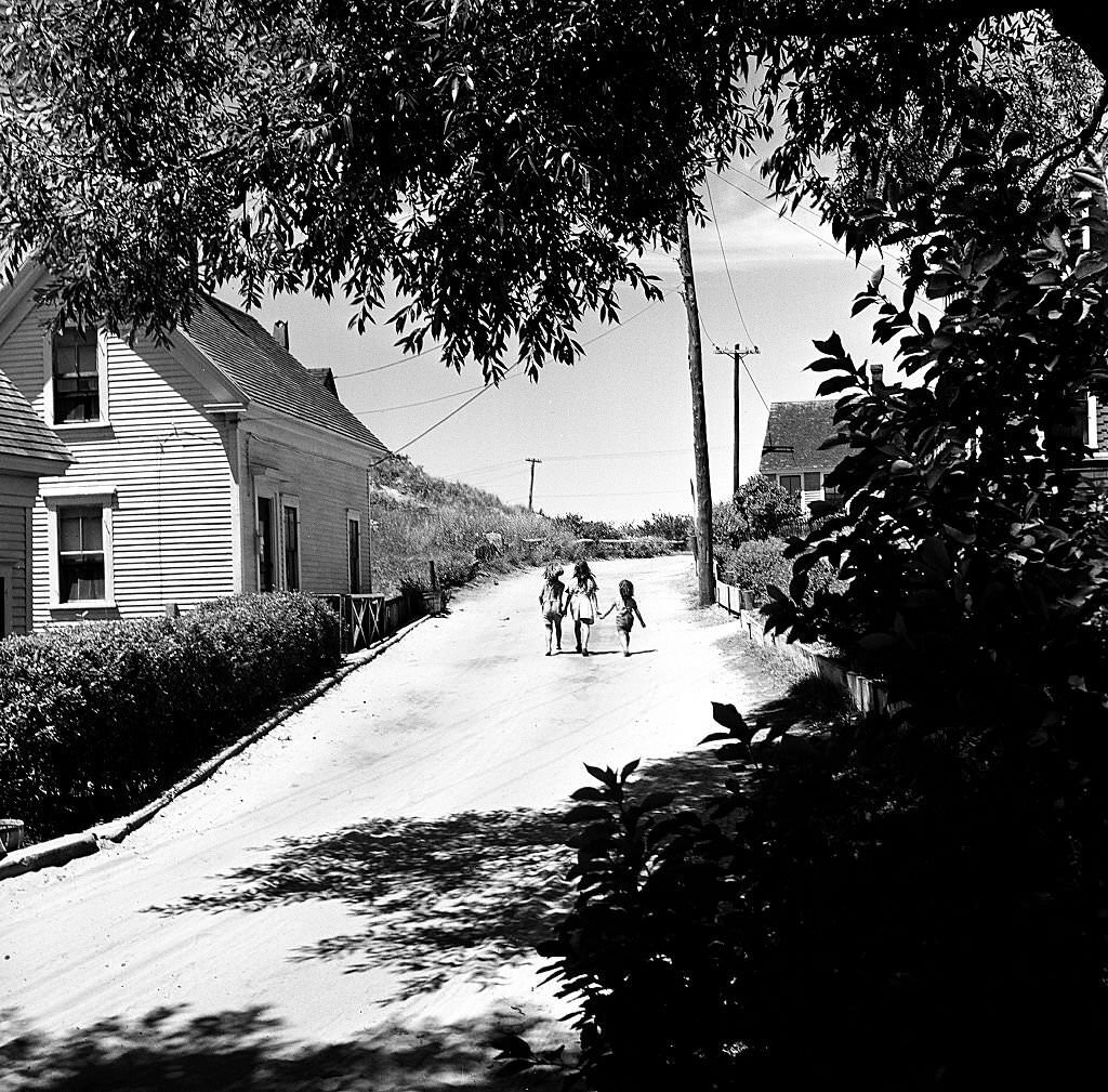 Three children hold hands as they walk up a street, Provincetown, Massachusetts, 1948.