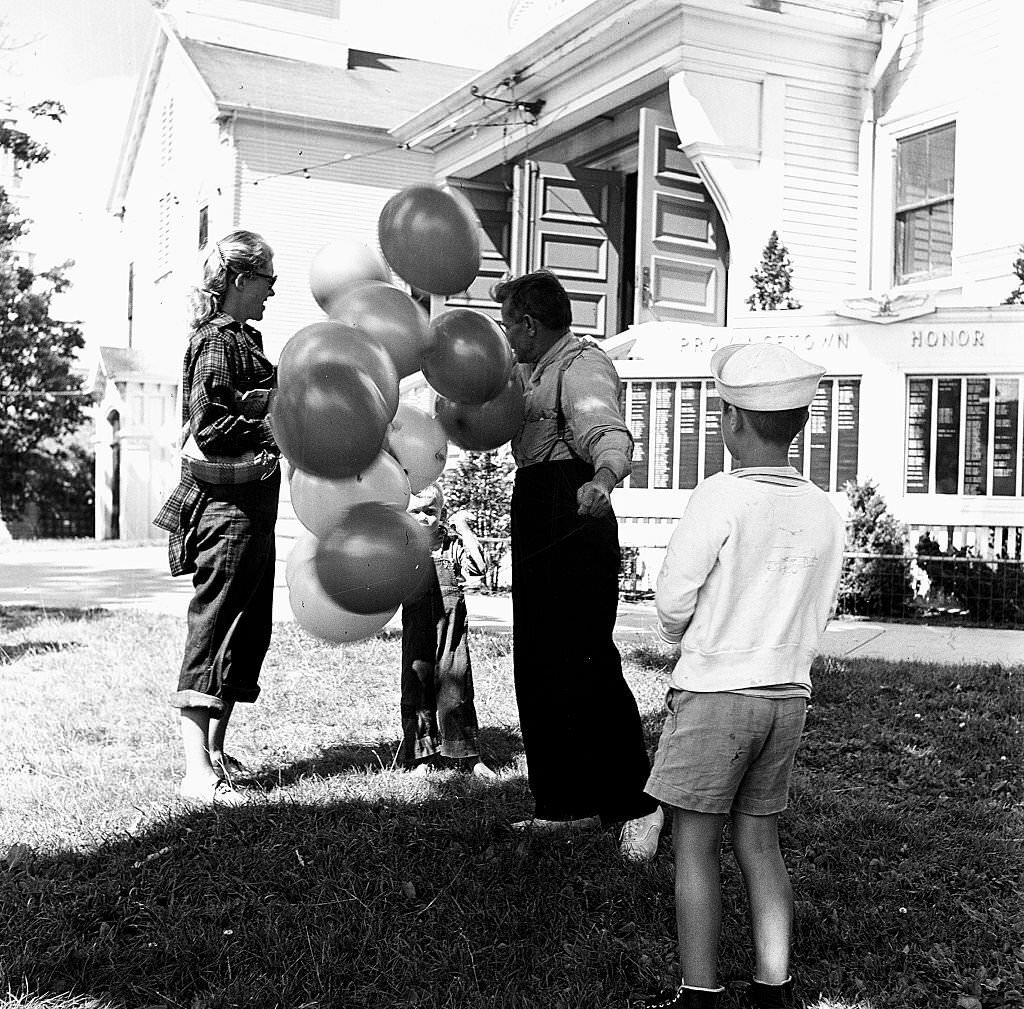 A young boy picks a balloon from a bunch sold by a balloon seller, Provincetown, Massachusetts, 1948.