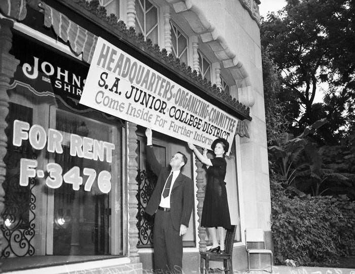 Robert Kingston and Mrs. Jerome Kuhl hang banner at headquarters for San Antonio Junior College, 1941