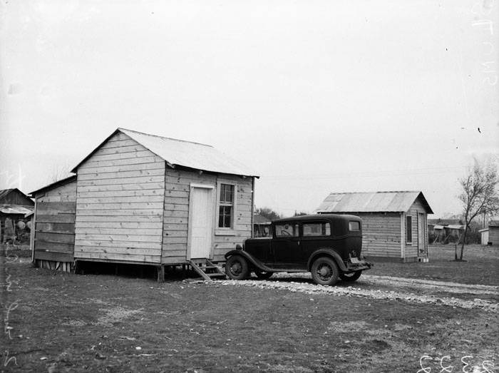 Automobile parked in front of small residence, 1940