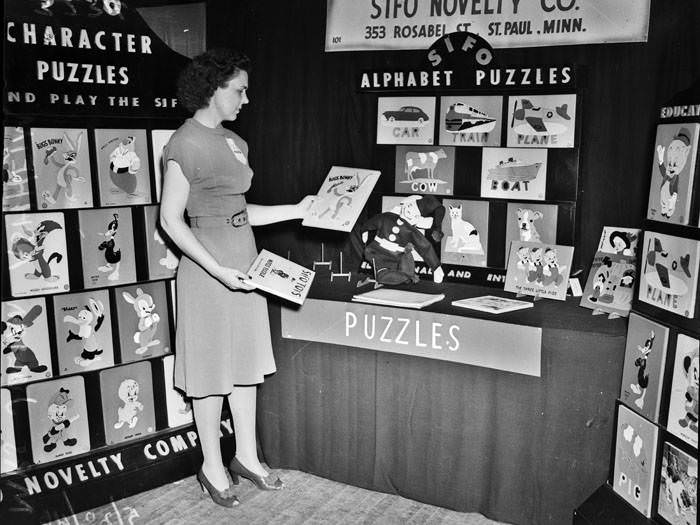 Mrs. Julian Ashheim looks over display of puzzles, 1946