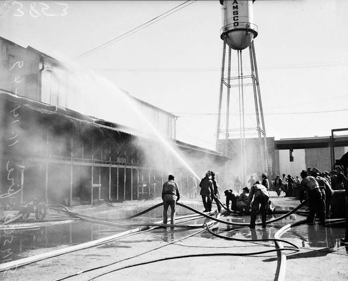 Firemen, with hoses, fight fire at San Antonio Machine & Supply Company, 1949