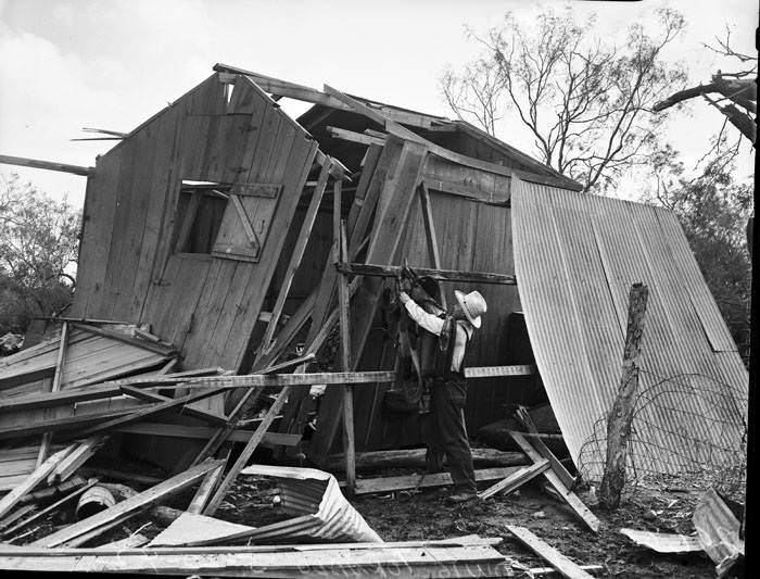 Man examines tornado damage to farm building, 1942