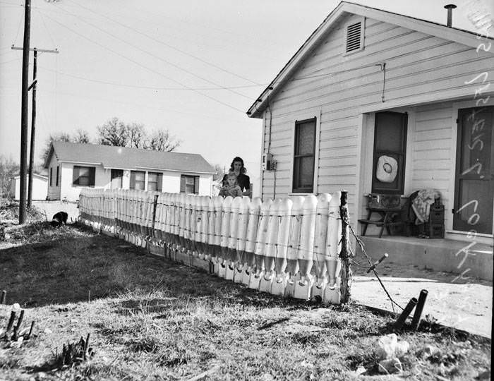 Mrs. Lester Lockhart poses with daughter behind fence, 1947