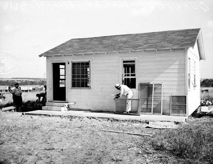 Man prepares to hang window screen on Quali-Cut residence, 1948