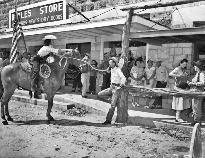 Cowgirl on horse roping a bystander on Main Street, 1948