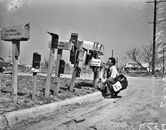 Postman H.L. King at row of mailboxes, 1947