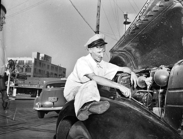 Jack Wiley looks at automobile engine, 1942