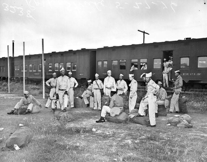 African American soldiers wait outside of train, 1946