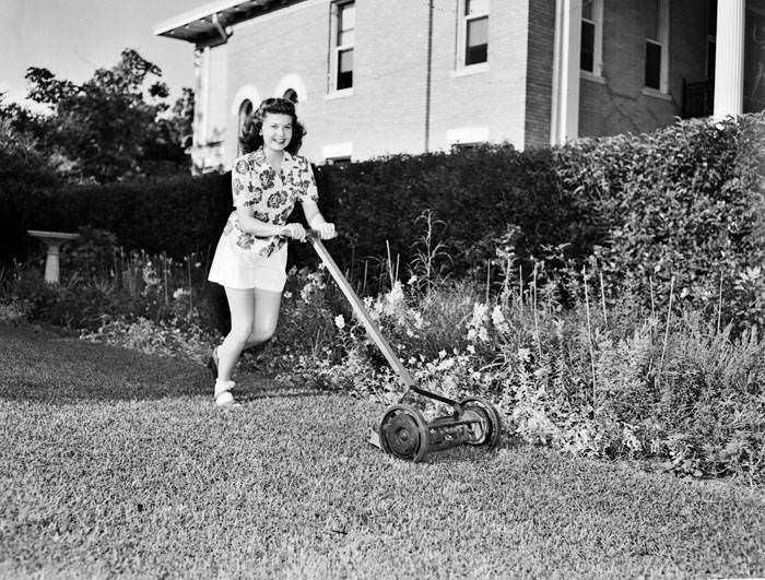 Miss Pat Holden mowing lawn, 1946