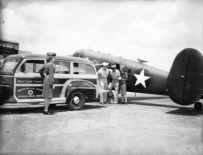Red Cross motor corps members prepare to transport patient from plane to automobile, 1942