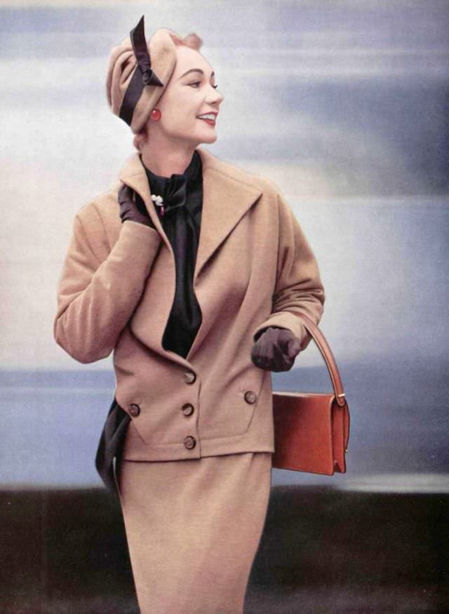 Sophie Malgat in elegant jersey suit, jacket has neck and wide lapels that open on silk surah blouse by Lucille Manguin, hat is by Jean Barthet, leather handbag by Innovation, 1952