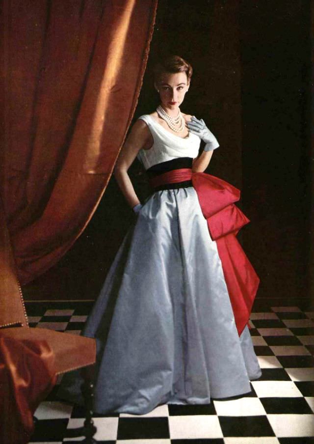 Sophie Malgat in evening gown, the bodice is white chiffon with blue satin skirt and red satin sash over wide black satin waist band, by Jacques Fath, 1952