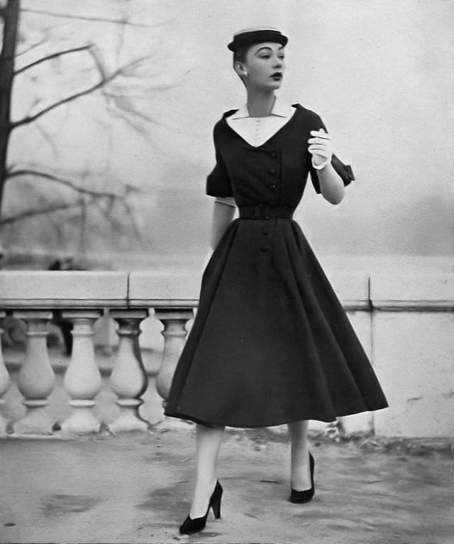 Sophie Malgat is wearing a thin blue wool dress with deep décolletage filled with white linen, has linen undersleeves, by Jean Patou, Harper's Bazaar, April 1952