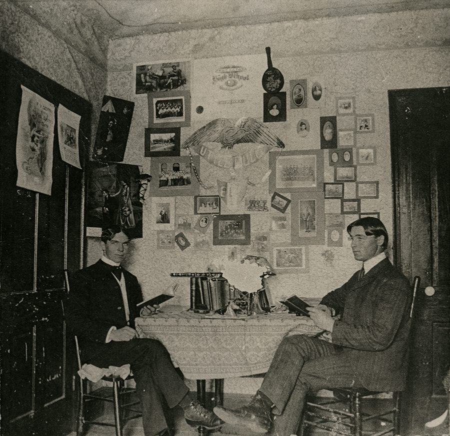 Two students study in their well decorated dorm room, 1890s