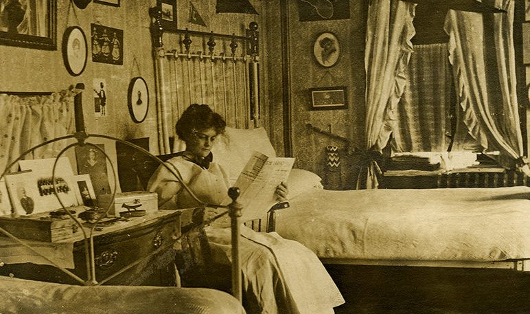 Young girl student reading a newspaper in her room at Georgia Burleson Hall, Baylor University, 1910