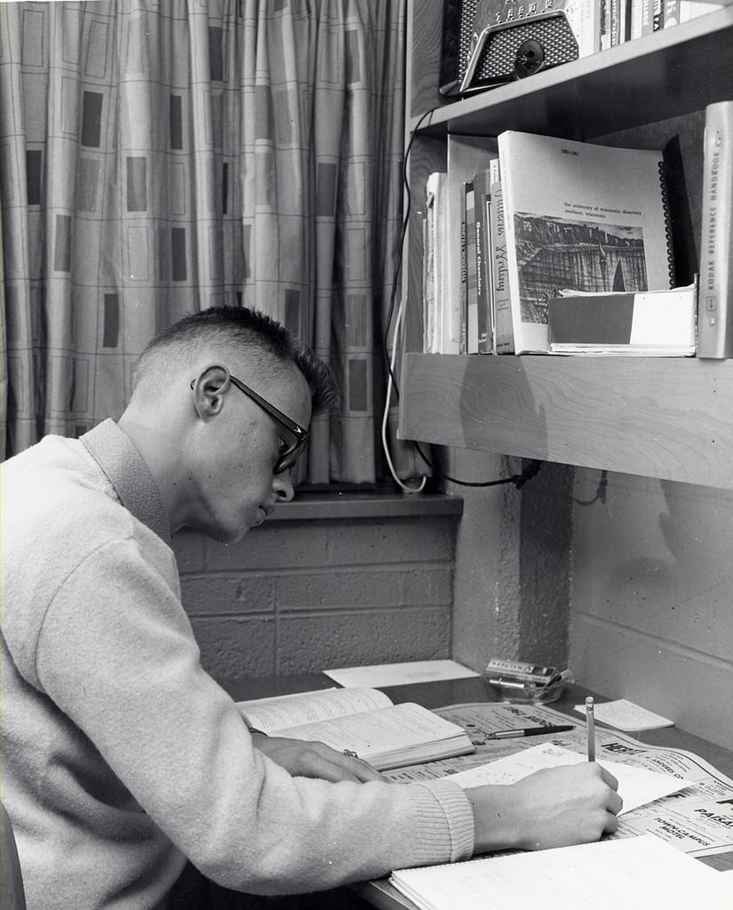 A guy studying in dorm room, 1950s.