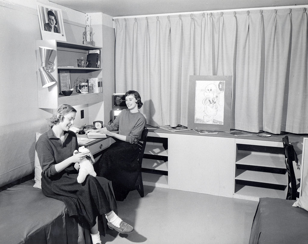 Two women sitting in mock-up dorm room in Chadbourne Hall, 1950s