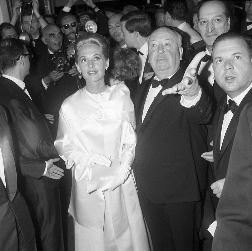 Tippi Hedren and Alfred Hitchcock at Cannes surrounded by photographers, 1963