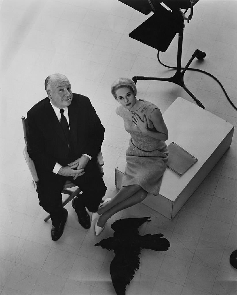 Alfred Hitchcock and leading lady Tippi Hedren pose with a stuffed raven on the set of the film 'The Birds, 1963.