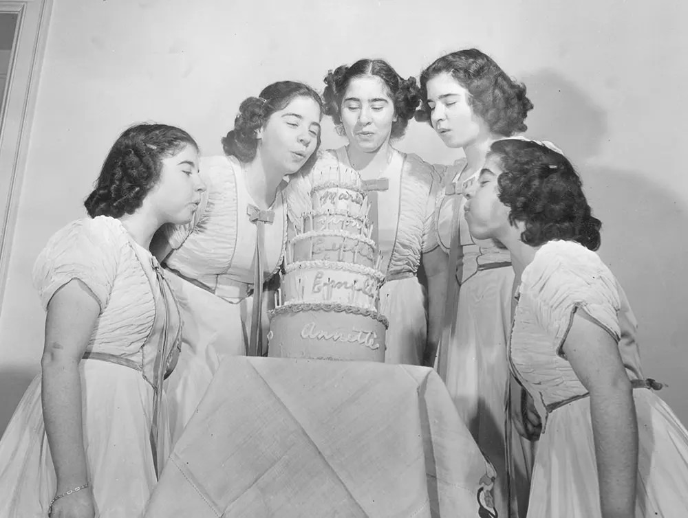 Annette, Cecile, Marie, Yvonne and Emilie blow out the candles on their five-tiered 14th birthday cake, 1948.