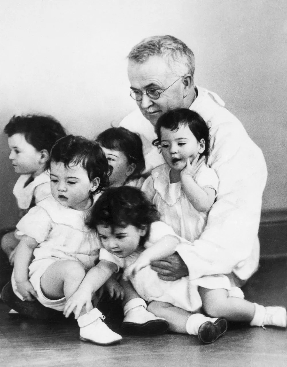 Delivering physician Dr. Allan R. Dafoe visits the quintuplets on their first birthdays, 1935.