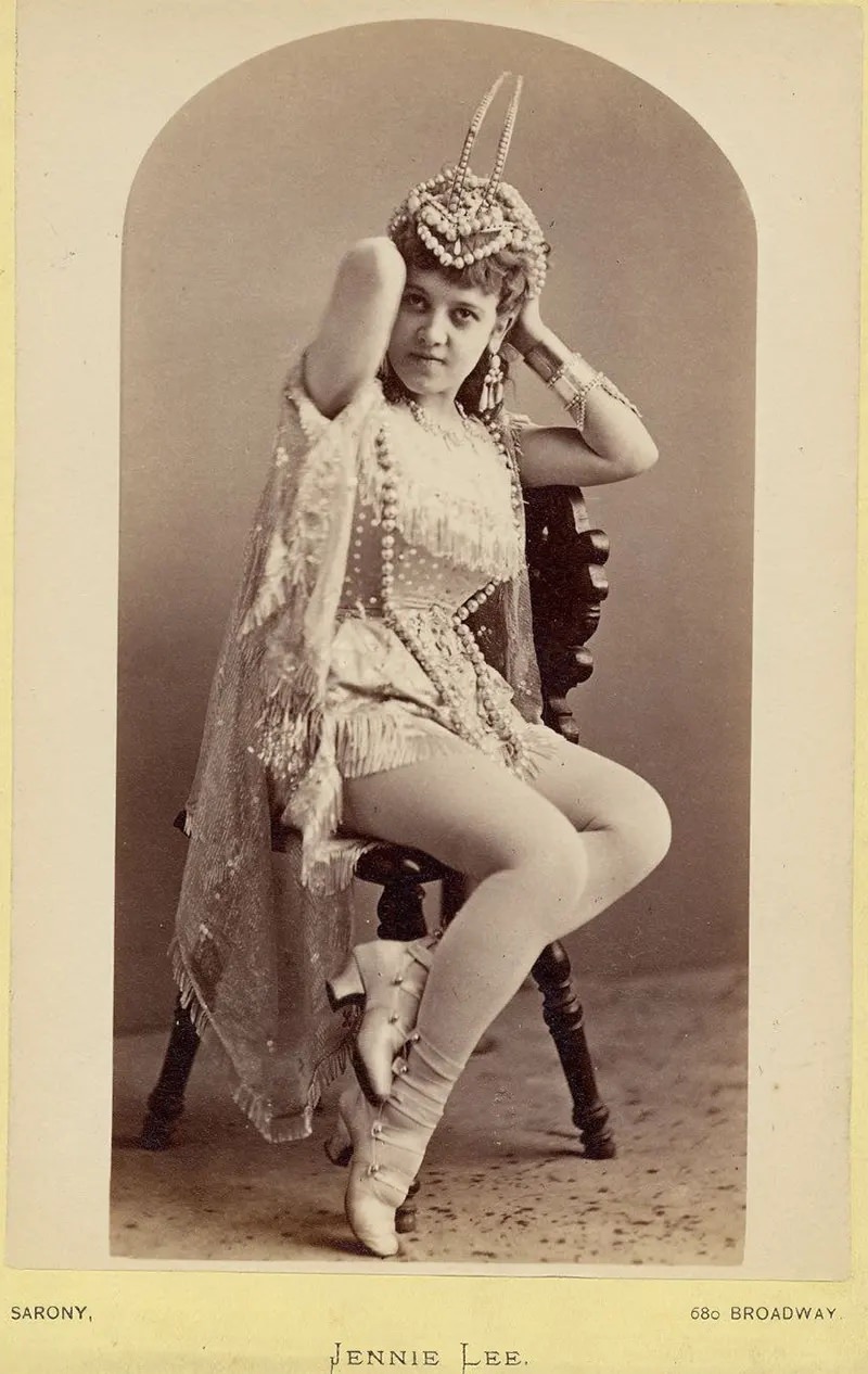 Jennie Lee sitting on a chair holding a headdress.