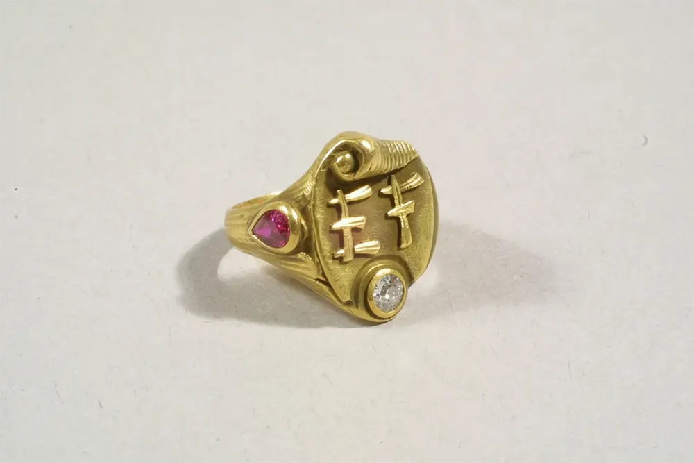 A gold mourning ring with a ruby and diamond and the initials EF in an Asian-style script.
