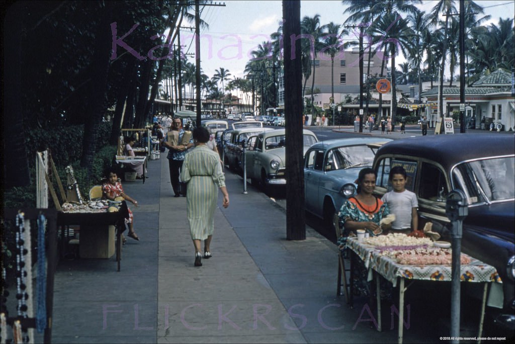 Aunty Bella's amidst the sidewalk sellers along Waikiki’s Kalakaua Avenue on the street frontage of the Royal Hawaiian Hotel, 1957