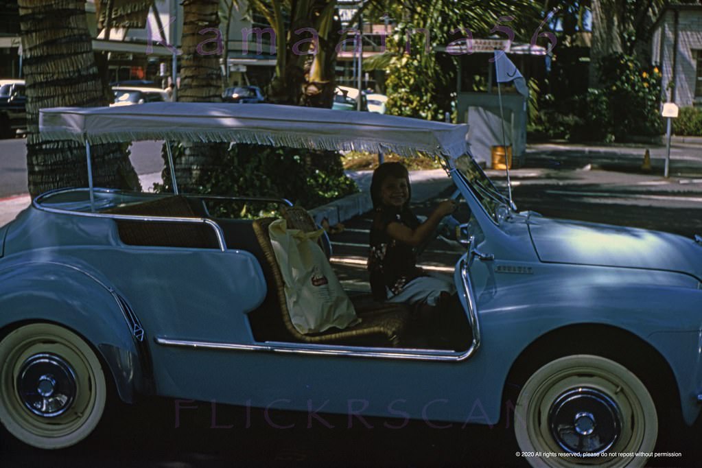 Cute keiki behind the wheel of a rare 1960 Renault Ghia 4CV Resort Special in the wild. View is from the Ewa (west) side of Royal Hawaiian Avenue looking makai (seaward) towards Kalakaua Avenue, 1960s